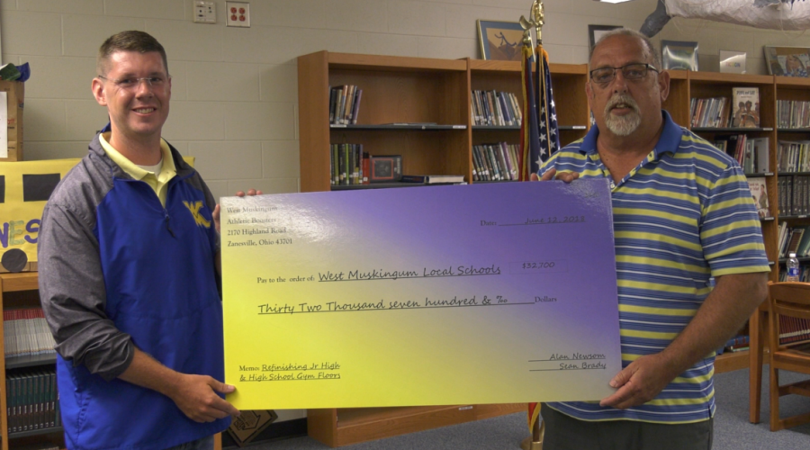 President of the West Muskingum athletic boosters Sean Brady (left) poses with the check issued by the group to the school district with Board of Education President Ab Vousden.
