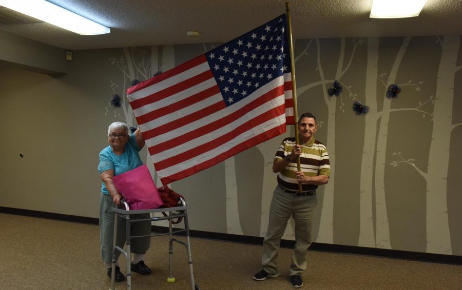 Two seniors at the Carr Center hold up the inside American Flag used for the Pledge of Allegiance in the center when the weather doesnt allow for the pledge outside.