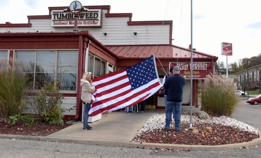 Members from the Carr Center unfold and raise the new America Flag up the flagpole outside of the Tumbleweed restaurant Wednesday, Nov. 7.