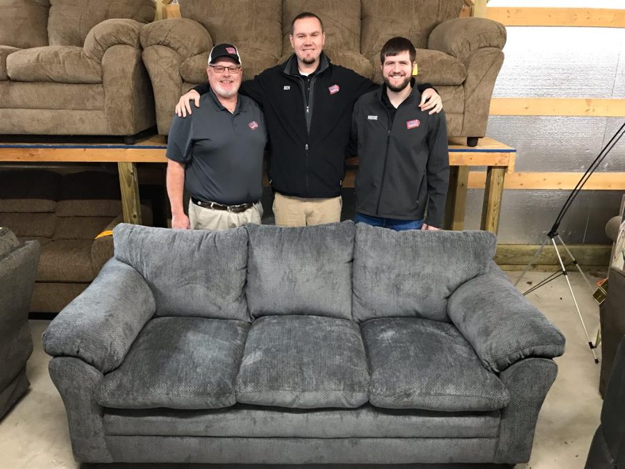 Paul Lowe (left), Big Ben Lowe (center) and Robbie Hisey (right) stand behind the beautiful new sofa Lowes Bargain Barn Furniture is giving away to thank their customers during the holiday season.