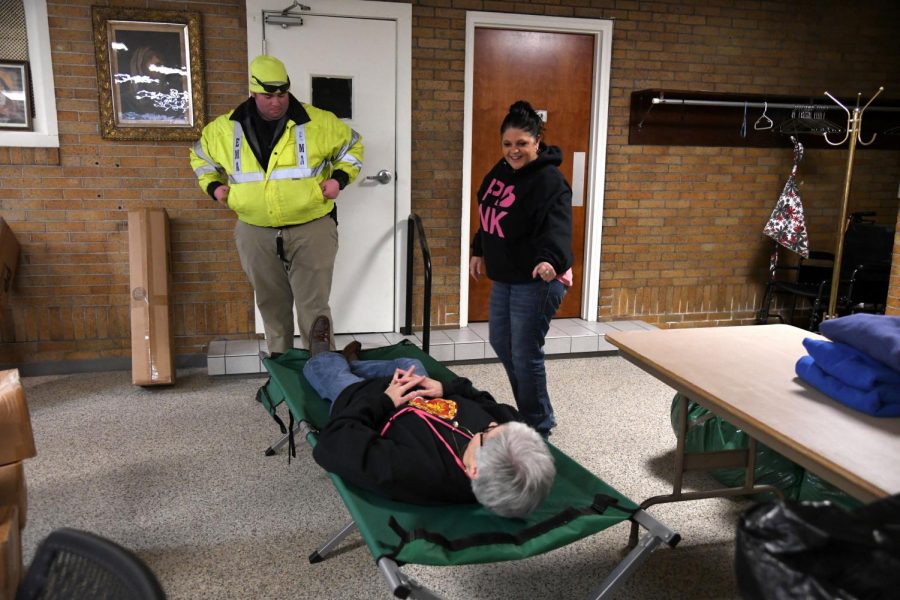 Kandice Longstreth, Outreach Coordinator for St. Thomas Aquinas Catholic Church, tries out a cot in the warming shelter as Tammy Clark, President of Homeless Hands of Zanesville and Travis Roach, Deputy Director of the Muskingum County EMA supervise.