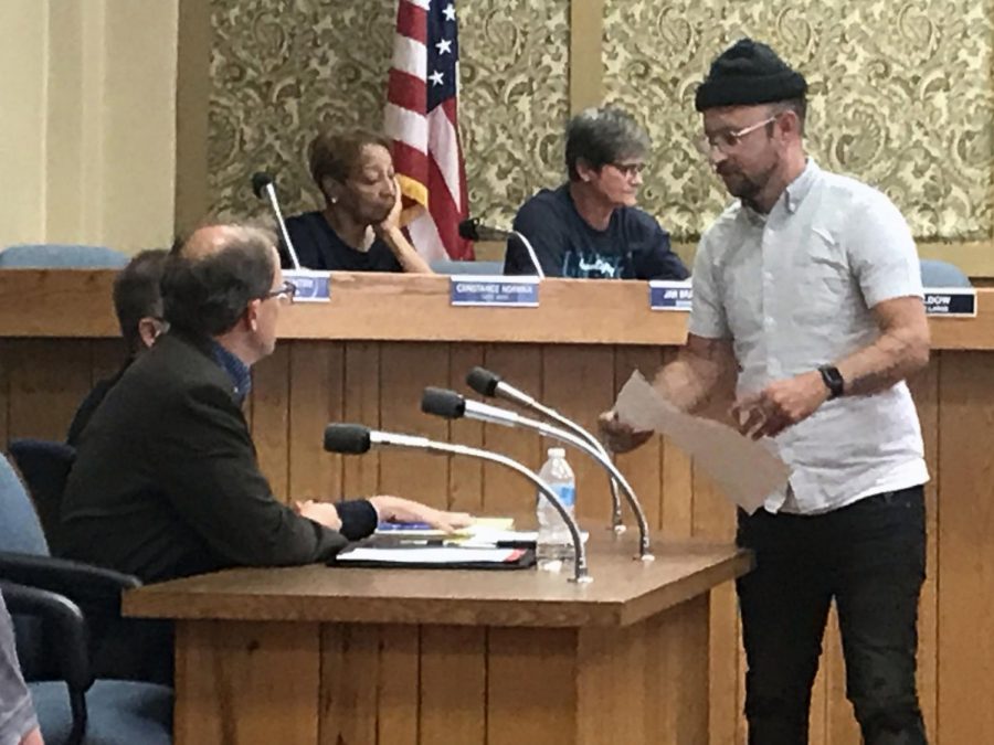 Nate Embrey hands a copy of his proposed plans to Council President Dan Vincent. 