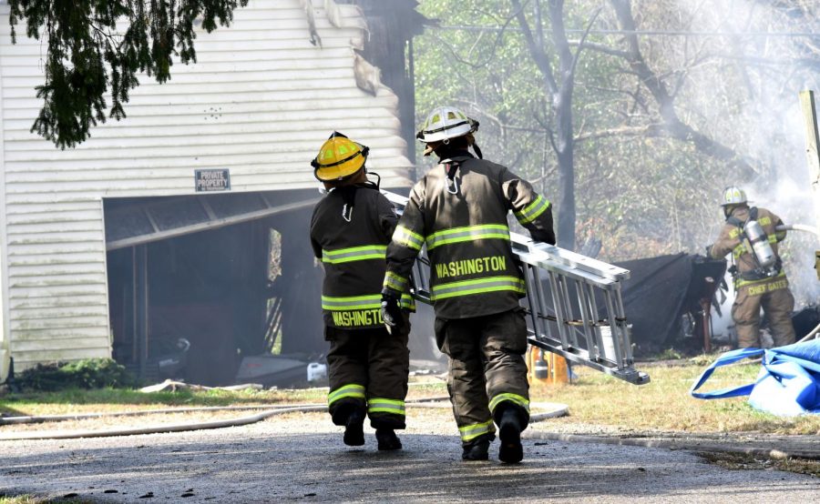 Two Washington Township Firefighters work to carry a ladder toward a burning garage on Sonora Road during a fire last October.