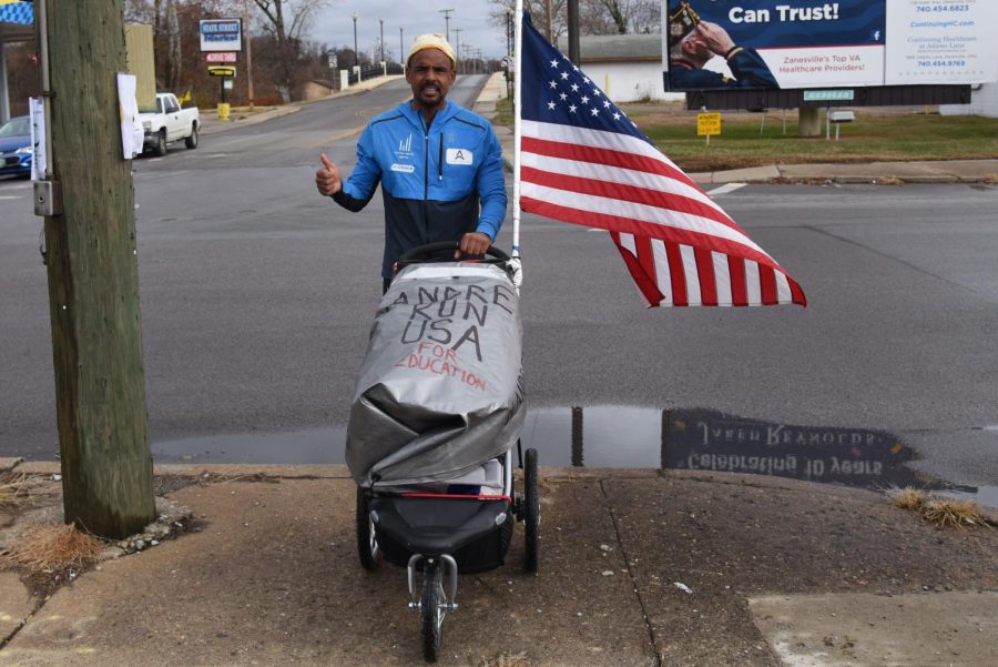 Andre Belibi Eloumou takes a break from running along W. Main Street in Zanesville to share his cause. He arrived in Zanesville Thursday night after running 25 miles from Cambridge. 