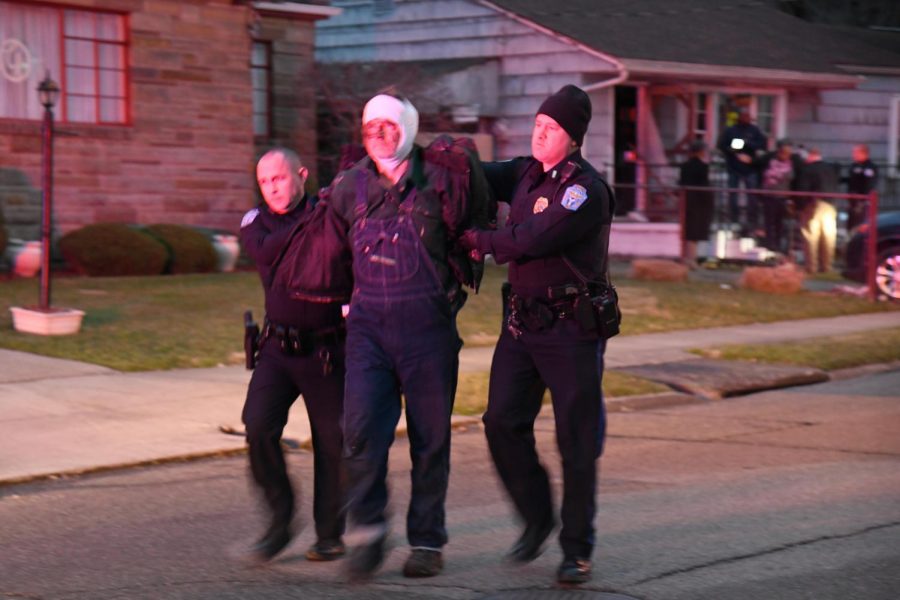Officers escort Michael Perdue to a police cruiser in handcuffs.