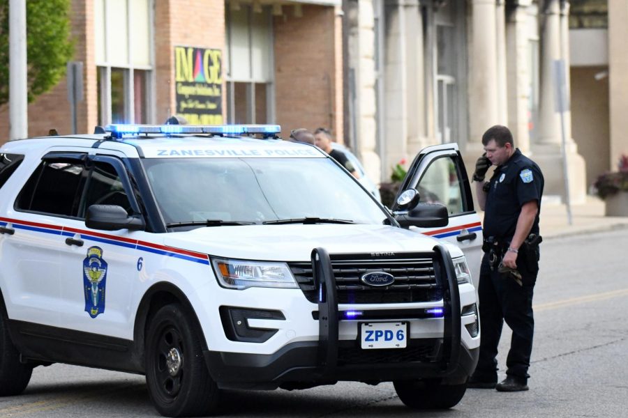 Officer Charles Lewis stands outside a patrol vehicle during an incident in Downtown Zanesville in September. 